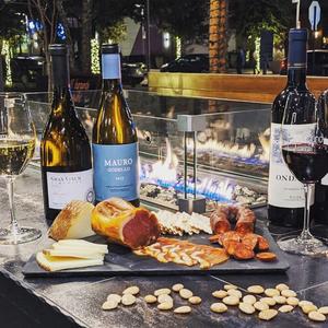 Local wine bar patio with fire. Enjoy a glass of red, white, bubbly or rose along with small bites including the pictured charcuterie. 